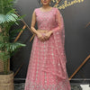 Woman in pink embroidered Indian ethnic lehenga and dupatta standing by a plant at Anandi Fashions boutique