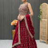Woman in a maroon Indian ethnic lehenga with intricate gold embroidery, matching dupatta and traditional jewelry, indoors