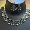Oxidized silver ethnic necklace and matching floral earrings with pearl details displayed on black stand