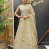 Woman wearing green embroidered Indian lehenga with matching dupatta, standing indoors by wooden screen and plant at Anandi Fashions