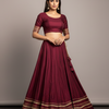 Woman wearing a maroon traditional outfit with a plain background