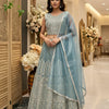 Woman modeling blue embroidered lehenga choli with sheer dupatta in elegant indoor setting at Anandi Fashions