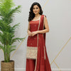 Woman wearing red Indian ethnic suit with embroidered kurta, matching dupatta and palazzo pants, posing indoors