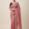 Woman wearing a pink saree with a white border on a beige background