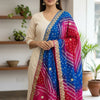 Woman wearing beige ethnic kurta with vibrant blue and red Bandhani dupatta with gold motifs indoors