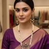 Indian woman wearing a purple silk saree with traditional gold and pearl jewelry in a boutique setting