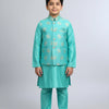 Boy in turquoise Indian ethnic wear kurta set with gold embroidery and beige traditional shoes