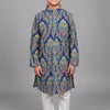 Smiling boy wearing blue floral patterned ethnic kurta with white churidar pants on gray background