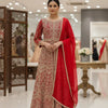 Woman wearing red and gold Indian ethnic floor-length anarkali suit with intricate embroidery and matching dupatta in boutique showroom