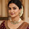 Close-up of woman wearing maroon embroidered saree, traditional Indian necklace and earrings with floral hair adornment in elegant setting