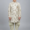 Boy wearing cream-colored traditional Indian sherwani with intricate patterns and churidar pants at Anandi Fashions