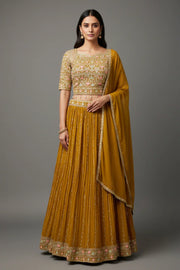 Woman in mustard yellow embroidered lehenga with floral patterns and matching dupatta from Anandi Fashions