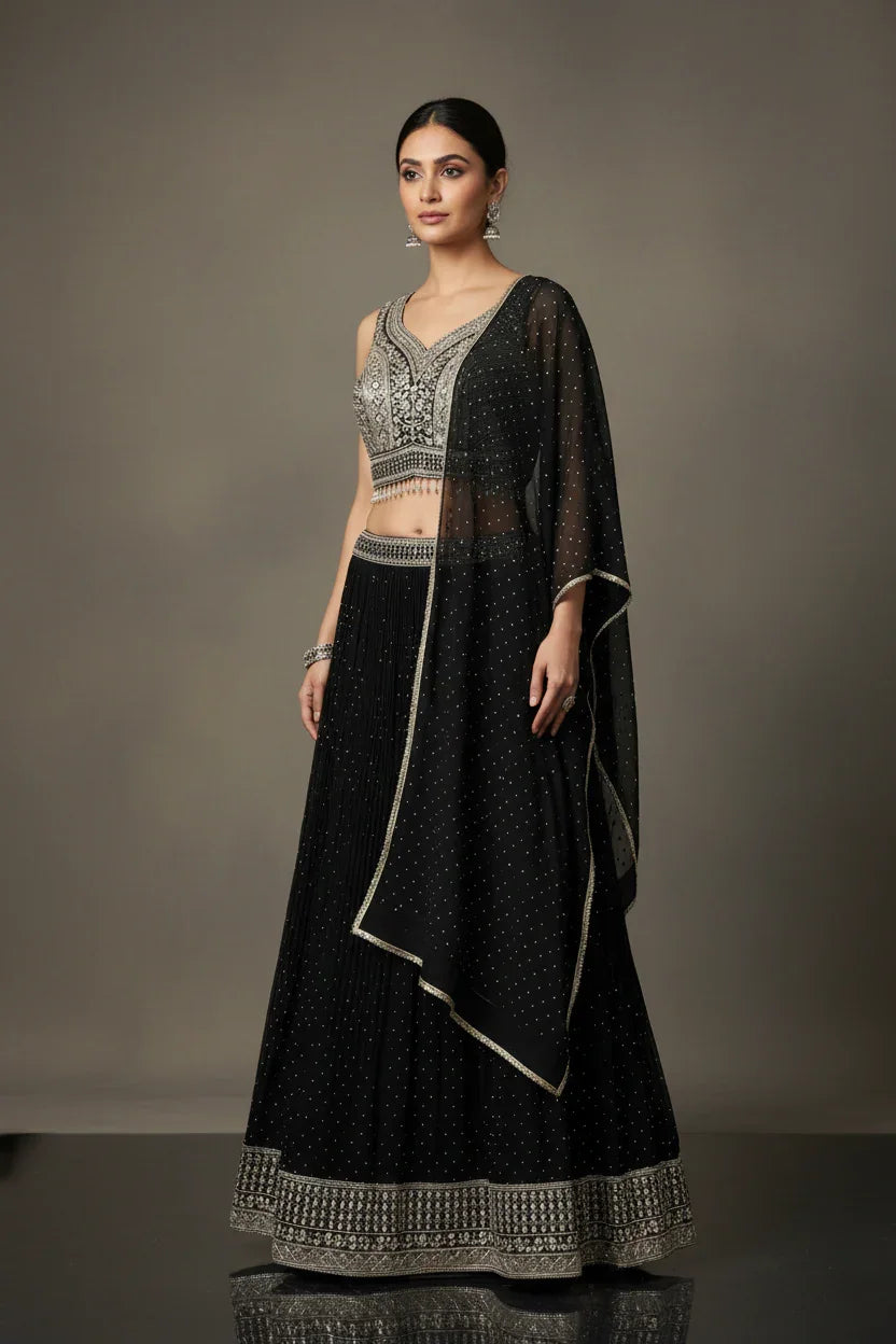 Woman wearing black Indian ethnic lehenga with silver embroidery and sheer dupatta, posing against neutral background