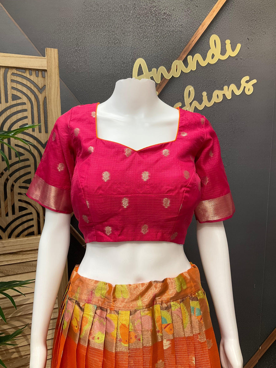 Mannequin wearing pink and gold embroidered blouse with orange floral silk lehenga, displayed at Anandi Fashions