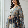 Smiling woman wearing white Indian ethnic dress with navy blue floral embroidered dupatta at window