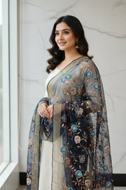 Smiling woman wearing white Indian ethnic dress with navy blue floral embroidered dupatta at window