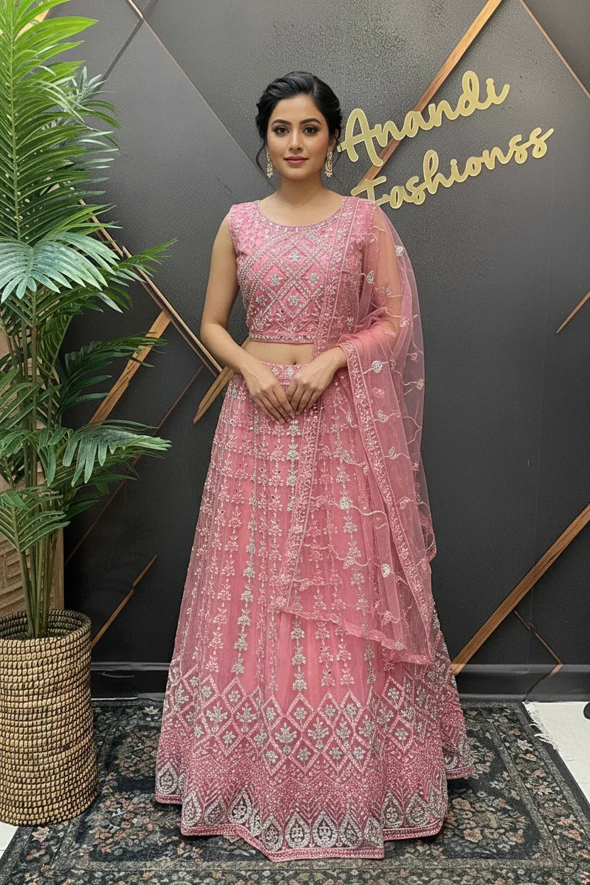 Woman in pink embroidered Indian ethnic lehenga and dupatta standing by a plant at Anandi Fashions boutique