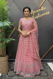 Woman in pink embroidered Indian ethnic lehenga and dupatta standing by a plant at Anandi Fashions boutique