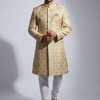 Man wearing a traditional beige sherwani with white pants on a light gray background