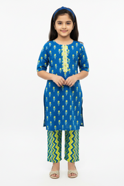 Young girl wearing a blue floral kurta with green and yellow pants on a white background