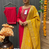 Woman wearing red embroidered Indian ethnic kurta with a yellow embroidered dupatta, gold earrings, posing indoors