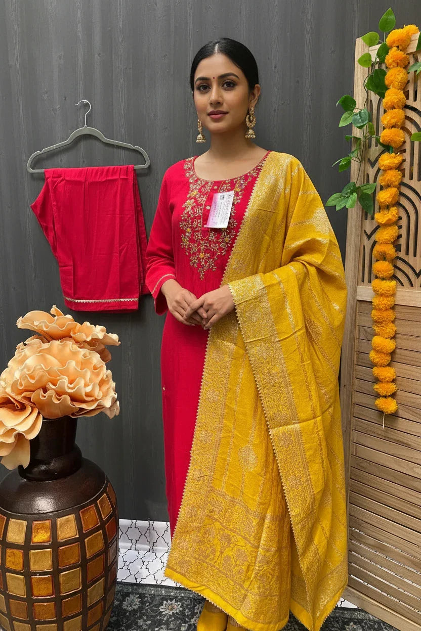 Woman wearing red embroidered Indian ethnic kurta with a yellow embroidered dupatta, gold earrings, posing indoors