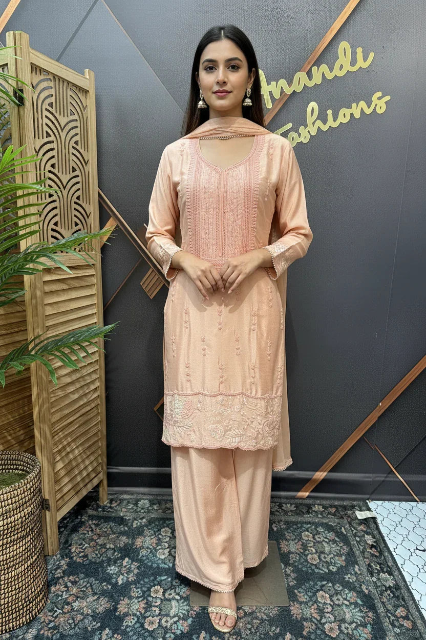 Woman wearing peach embroidered Indian ethnic wear with dupatta, standing indoors at Anandi Fashions showroom