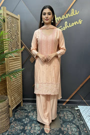 Woman wearing peach embroidered Indian ethnic wear with dupatta, standing indoors at Anandi Fashions showroom