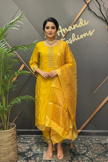 Woman wearing a yellow embroidered Indian ethnic suit with matching dupatta and jewelry at Anandi Fashions