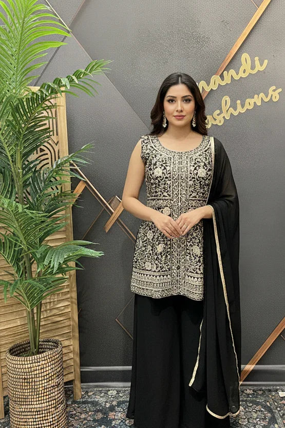 Woman wearing black and silver embroidered ethnic suit with dupatta standing indoors near plant at Anandi Fashions