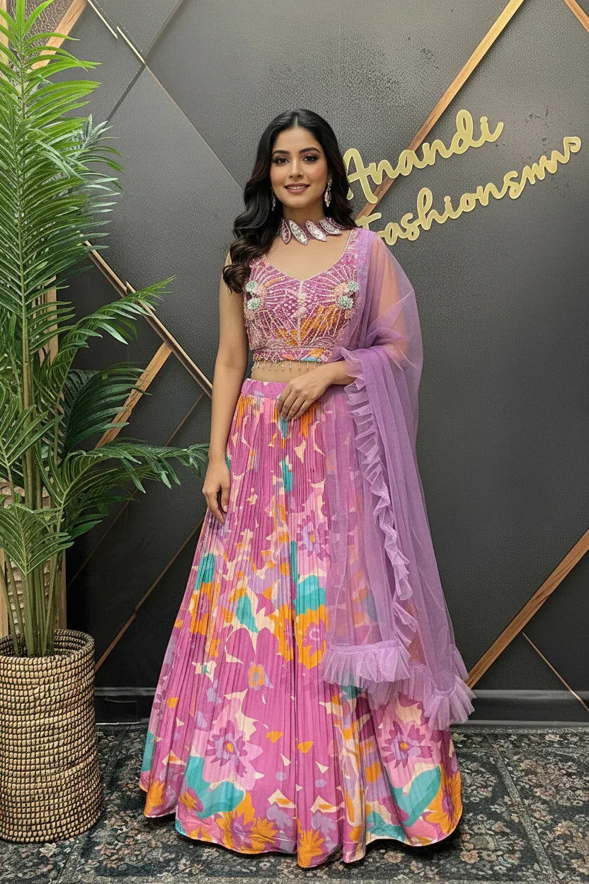 Woman in pink floral lehenga choli with sheer dupatta, standing indoors at Anandi Fashions boutique