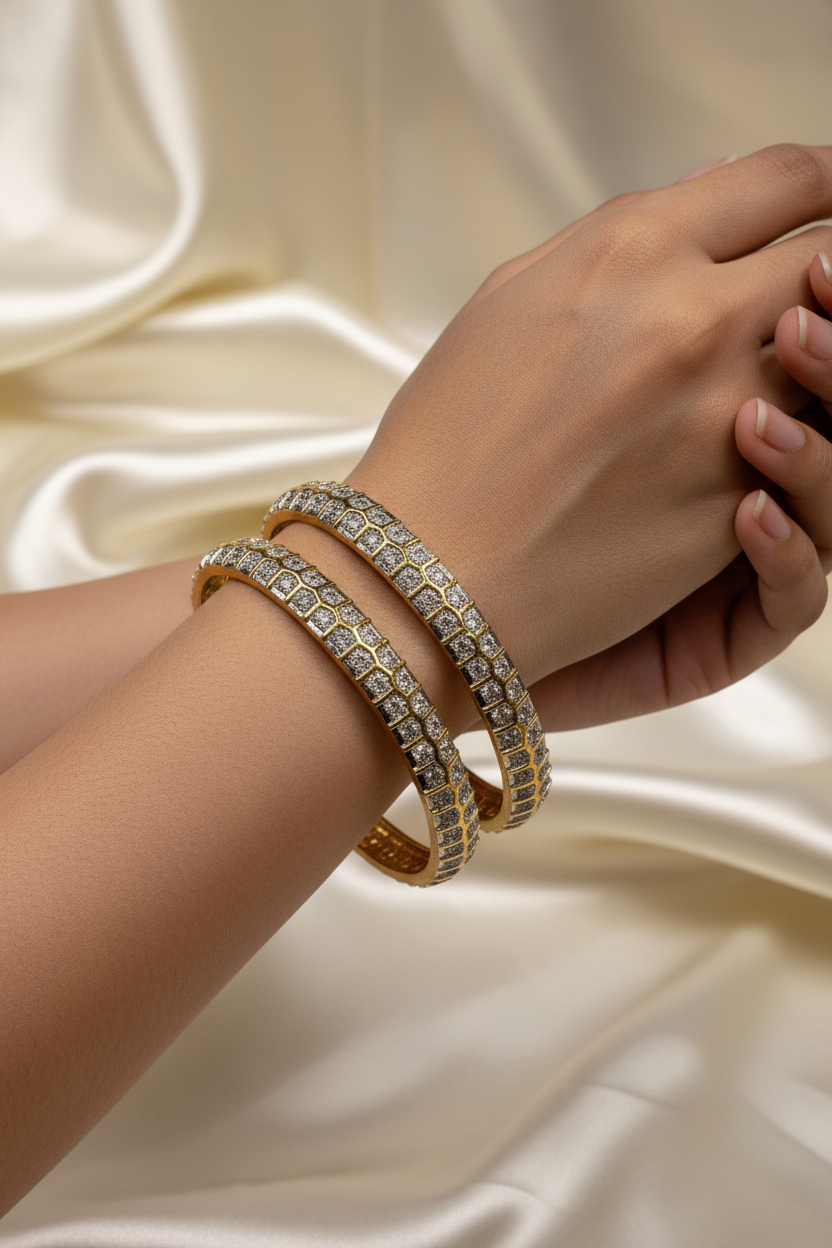 Close-up of hands wearing gold and diamond-studded Indian ethnic bangles on silky cream fabric