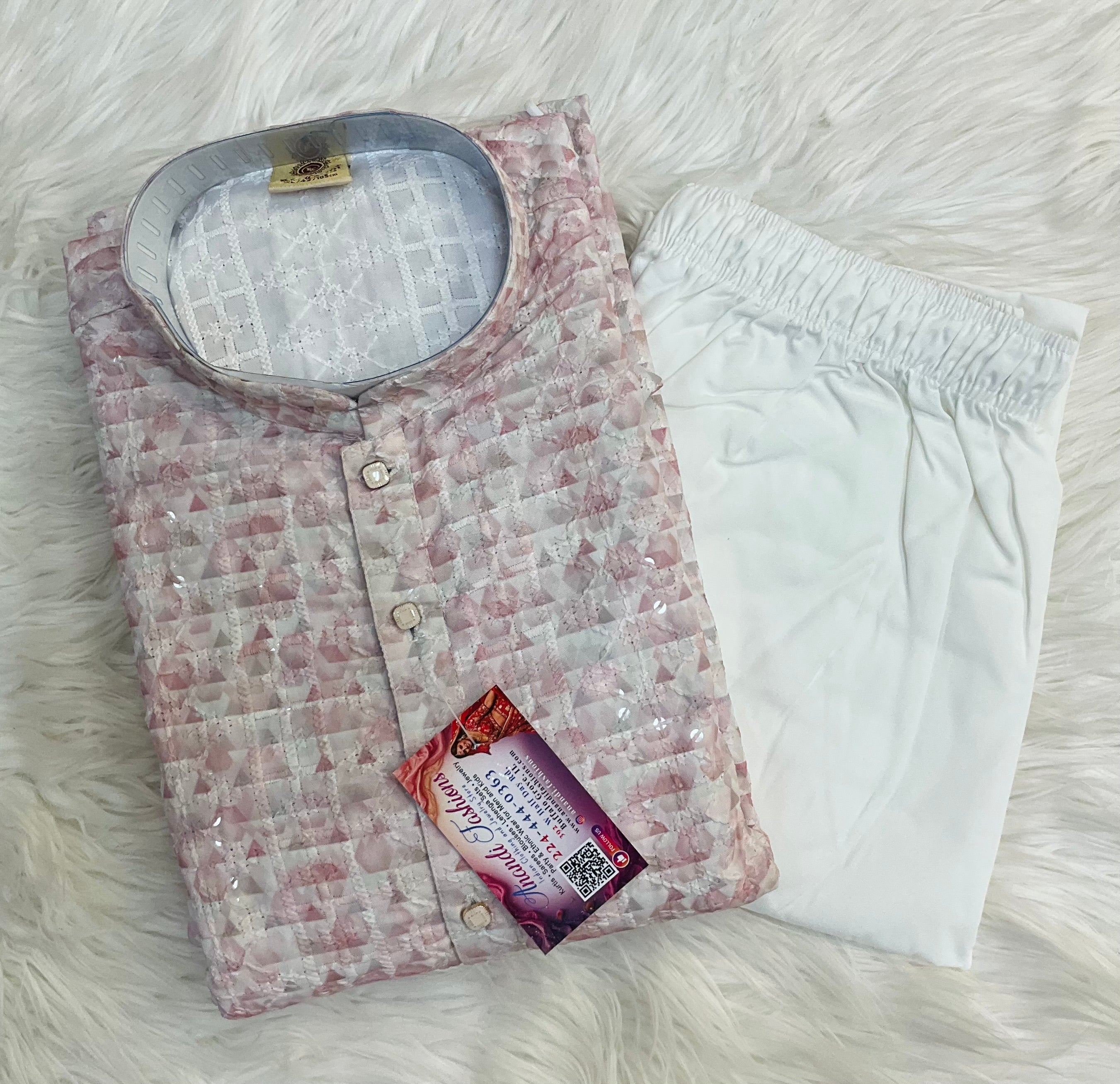 A folded two-piece men's pajama set on a white faux fur background. The set includes a light pink and white patterned quilted kurta with a stand collar and white drawstring shorts.