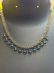Elegant Indian gold necklace with blue flower-shaped stones displayed on black stand
