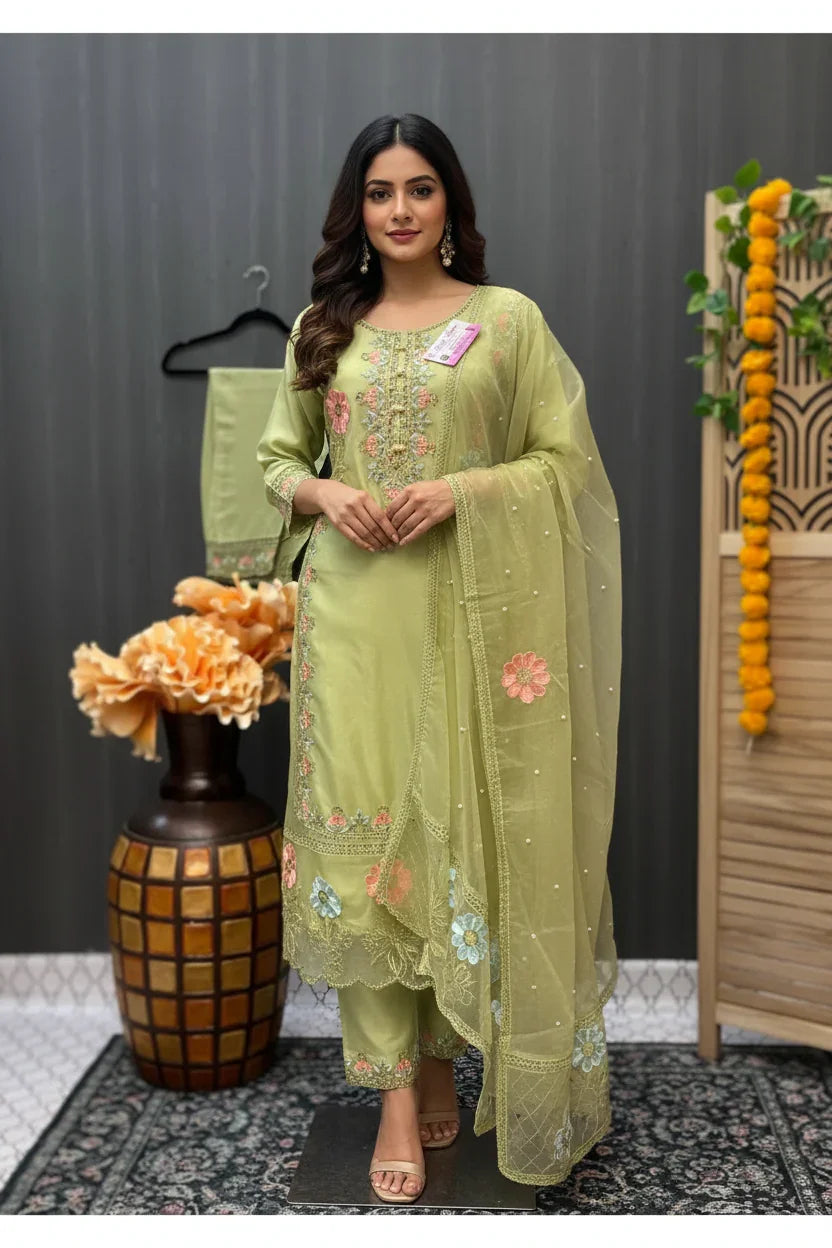 Woman wearing pastel green embroidered Indian ethnic suit with floral patterns and matching dupatta, standing indoors