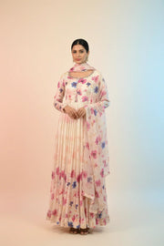 Woman wearing a cream floral printed Indian ethnic anarkali dress with dupatta and earrings