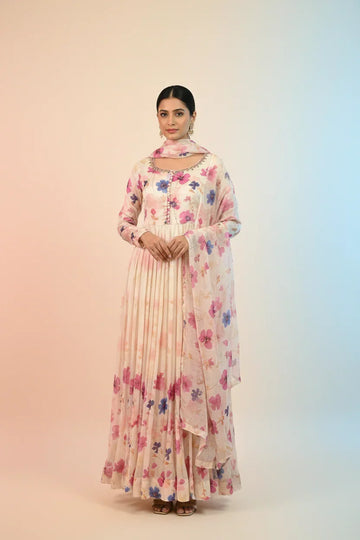 Woman wearing a cream floral printed Indian ethnic anarkali dress with dupatta and earrings