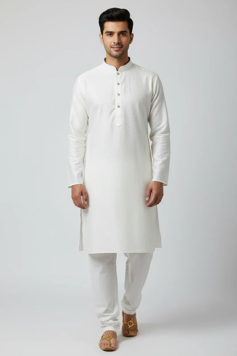 Man wearing elegant white Indian kurta with churidar and tan traditional sandals, studio background