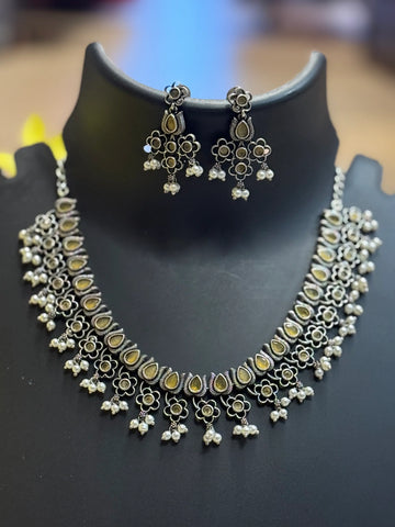 Traditional Indian oxidized silver necklace and matching floral earrings with pearl dangles on black display