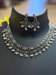 Oxidized silver ethnic necklace and matching floral earrings with pearl details displayed on black stand