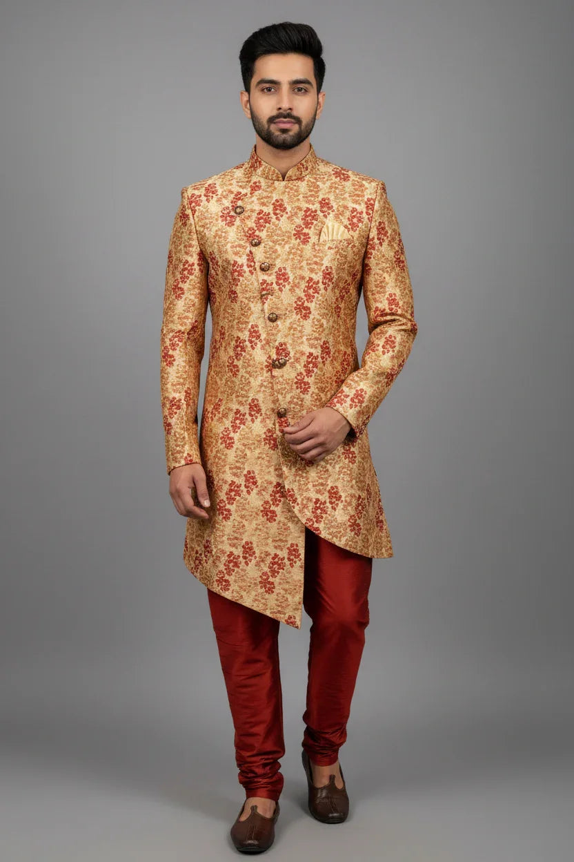 Man wearing gold and red floral patterned Indian sherwani with red churidar pants and brown traditional shoes