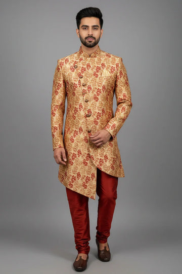 Man wearing gold and red floral patterned Indian sherwani with red churidar pants and brown traditional shoes