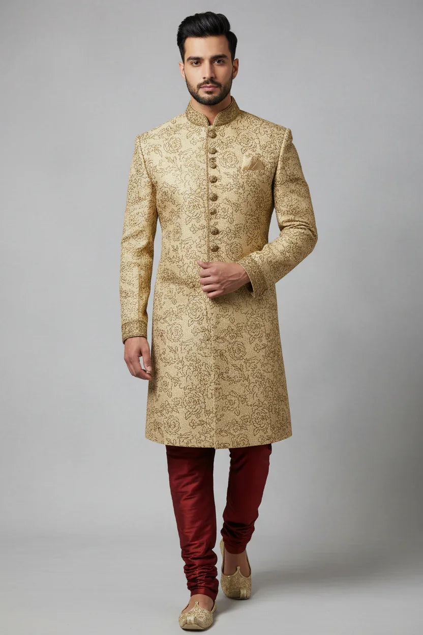Man wearing beige embroidered sherwani with gold buttons, paired with maroon churidar and beige mojari shoes