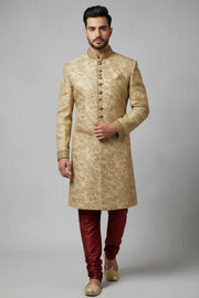Man wearing beige embroidered sherwani with gold buttons, paired with maroon churidar and beige mojari shoes