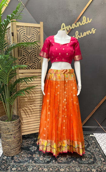 Mannequin wearing pink blouse and orange pleated ethnic skirt with floral border at Anandi Fashions