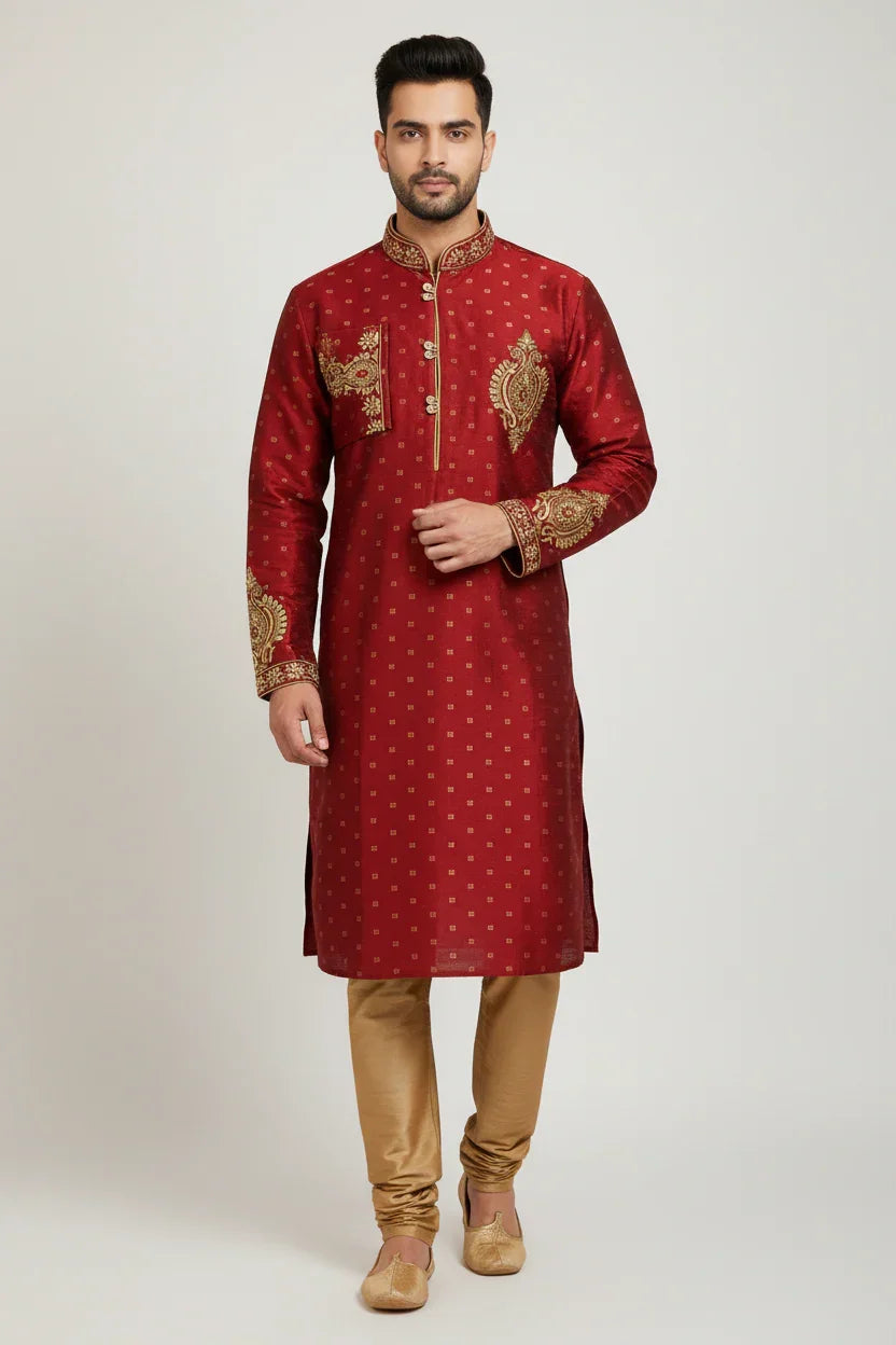 Man wearing traditional red Indian kurta with gold embroidery and beige churidar pants on plain background