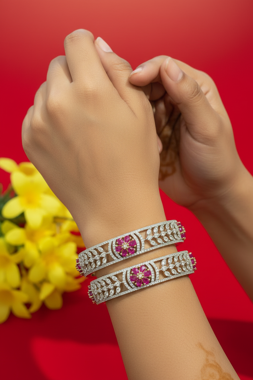 Close-up of hands wearing two ornate Indian diamond and ruby bangles against red background with yellow flowers