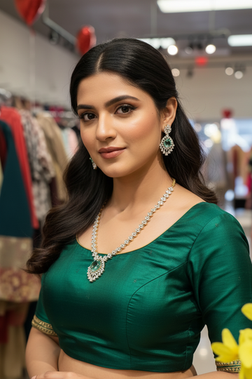 Woman in green ethnic blouse wearing elegant jewelry including emerald and diamond necklace and earrings at Anandi Fashions