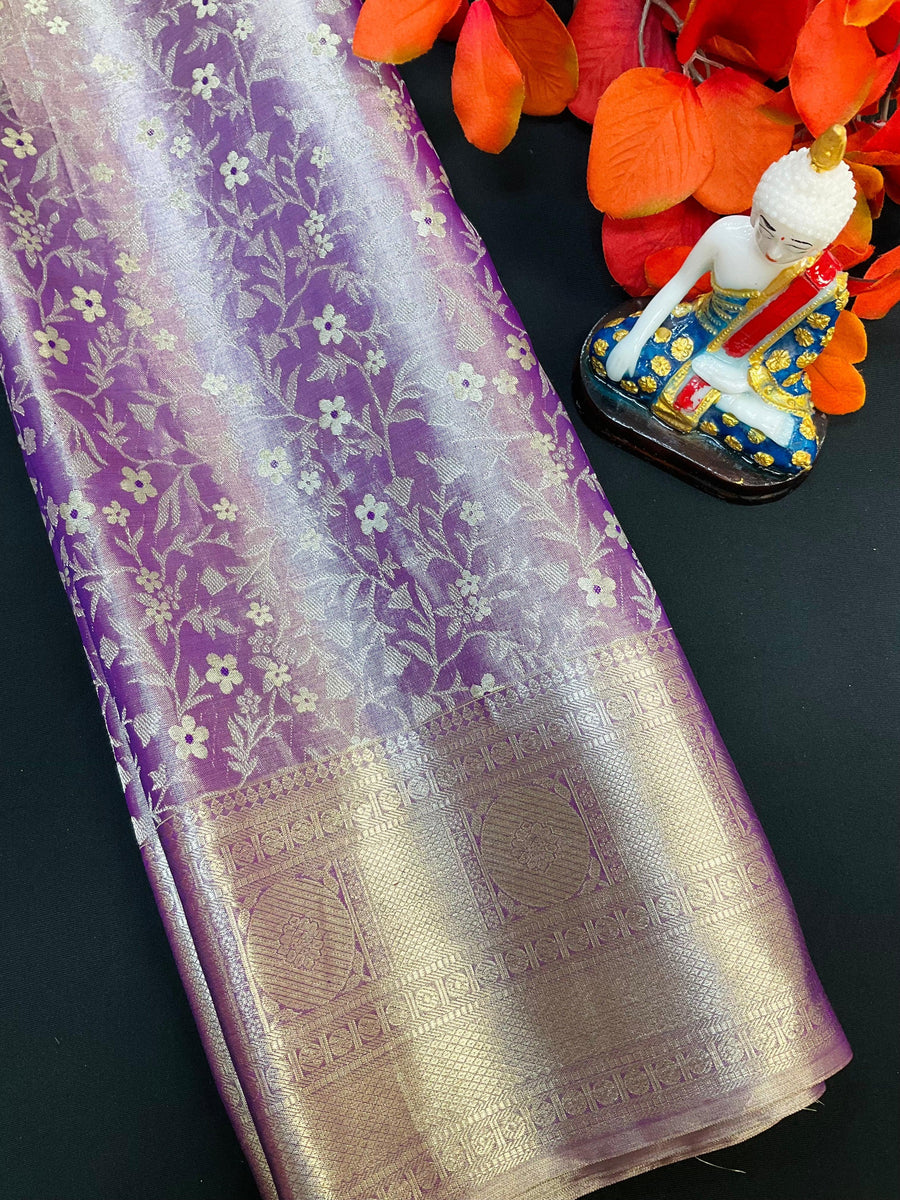 Purple Indian saree with gold floral zari work and intricate border, next to decorative Buddha statue and orange leaves