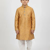 Boy wearing golden embroidered kurta, white churidar pants and traditional mojari shoes on white background